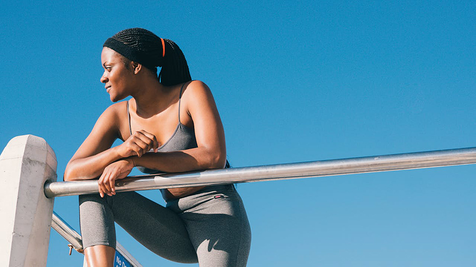 Kvinna vilar efter träning mot klar himmel