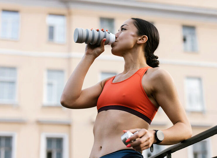 Kvinna dricker vatten efter träning utomhus