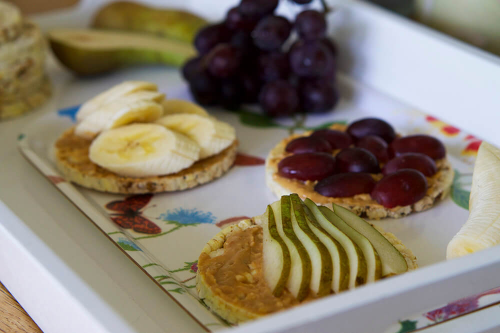 Frukostbricka med majskakor, jordnötssmör och frukt