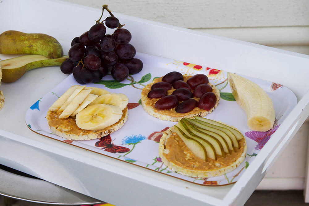 Frukostbricka med majskakor, jordnötssmör och frukt