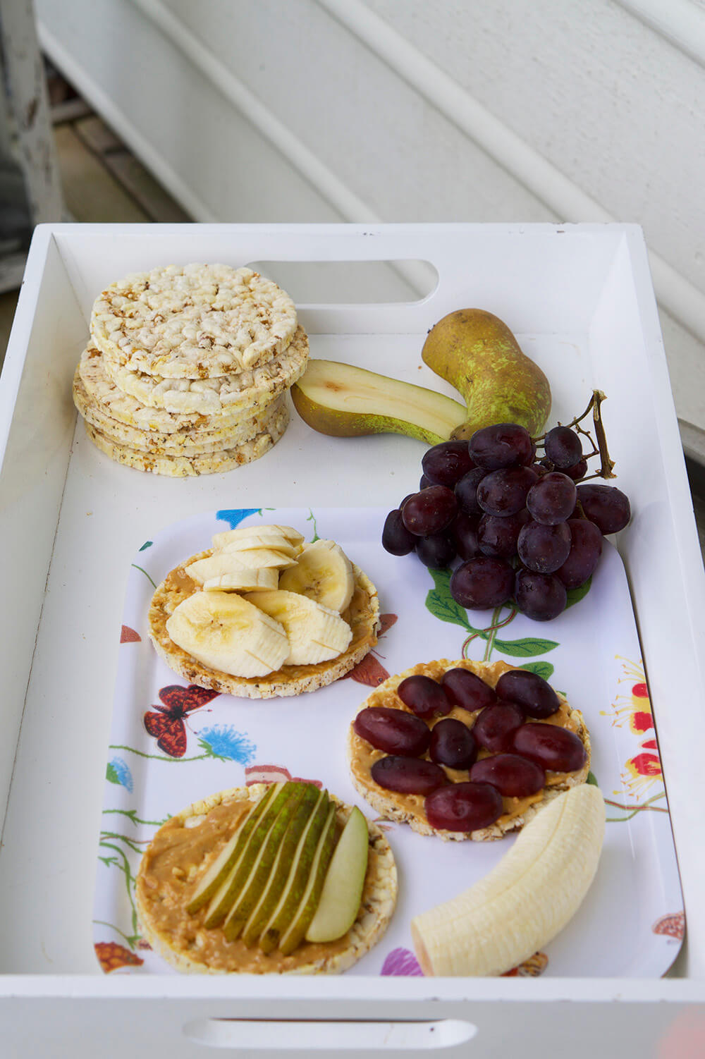 Frukostbricka med majskakor, jordnötssmör och frukt